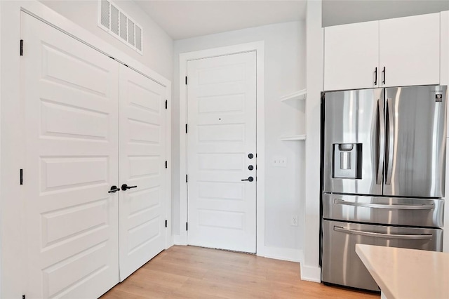 kitchen featuring visible vents, light wood-style flooring, white cabinets, and stainless steel fridge with ice dispenser