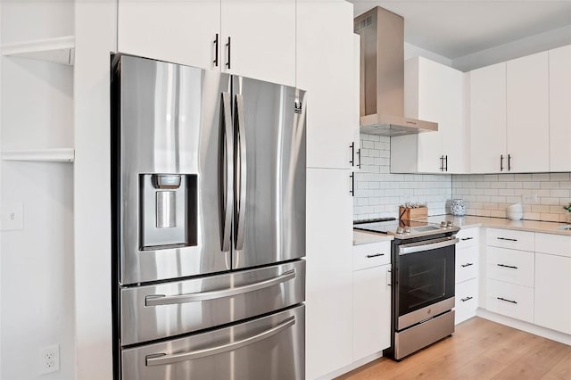 kitchen with light wood-style flooring, wall chimney range hood, backsplash, stainless steel appliances, and light countertops