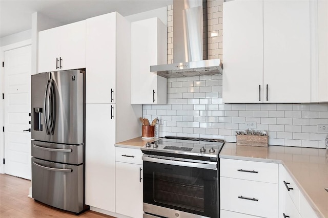 kitchen with light countertops, wall chimney range hood, tasteful backsplash, and appliances with stainless steel finishes