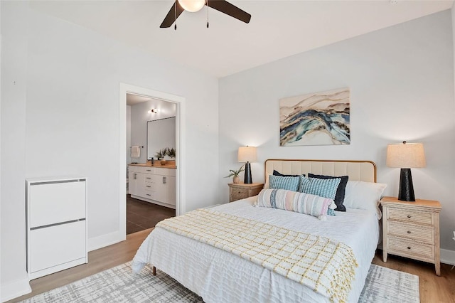 bedroom featuring wood finished floors, baseboards, and ensuite bathroom