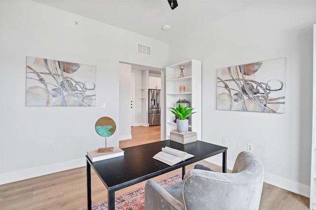 office area with light wood finished floors, visible vents, and baseboards