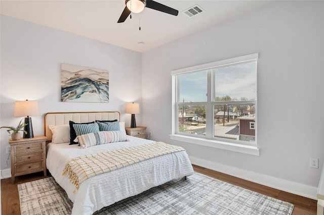 bedroom with a ceiling fan, wood finished floors, visible vents, and baseboards