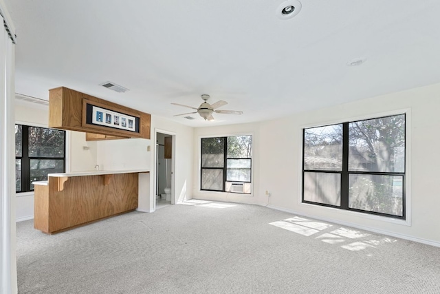 unfurnished living room with visible vents, baseboards, light colored carpet, and ceiling fan