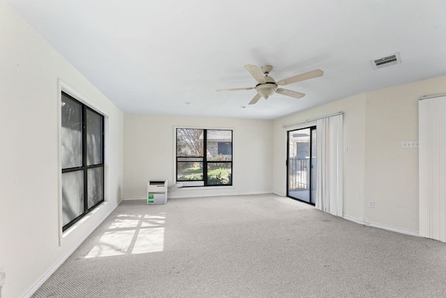 empty room with baseboards, a ceiling fan, visible vents, and light carpet