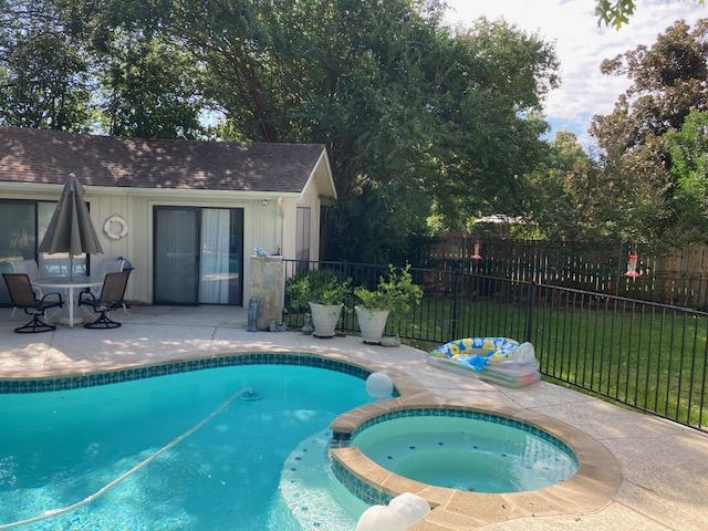 view of swimming pool with a yard, a pool with connected hot tub, a patio, and fence