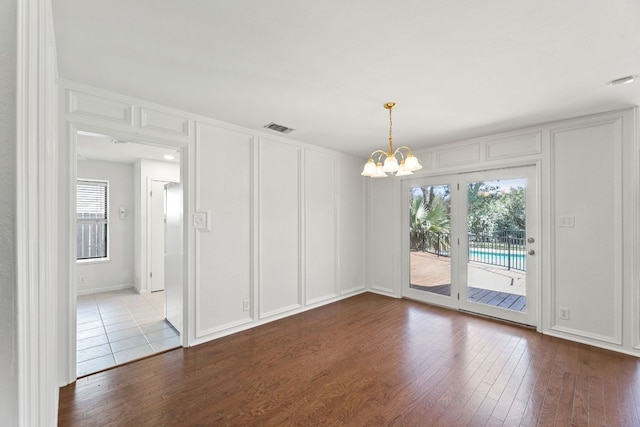 unfurnished room featuring a decorative wall, plenty of natural light, visible vents, and a chandelier