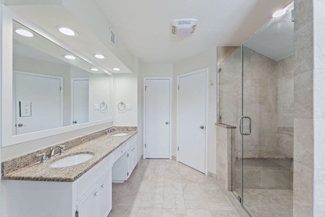 full bath with double vanity, visible vents, a stall shower, and a sink