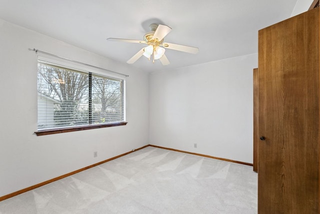 unfurnished room featuring a ceiling fan, light colored carpet, and baseboards