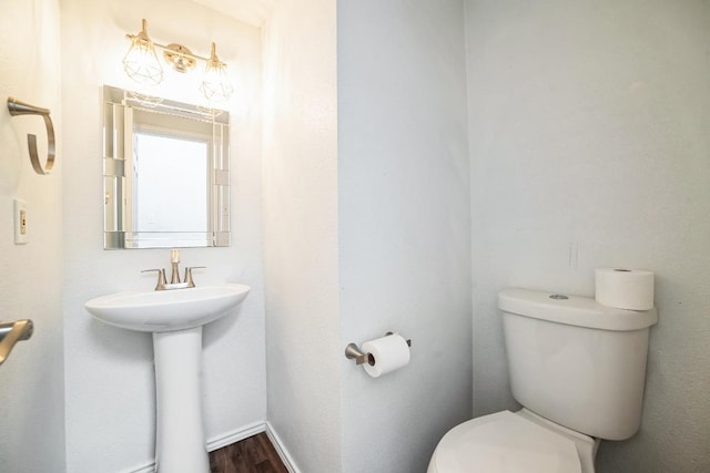 bathroom featuring a sink, baseboards, toilet, and wood finished floors