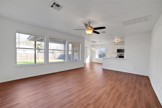 unfurnished living room featuring visible vents, ceiling fan with notable chandelier, and wood finished floors