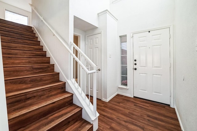 entrance foyer featuring stairs, baseboards, and dark wood-style flooring