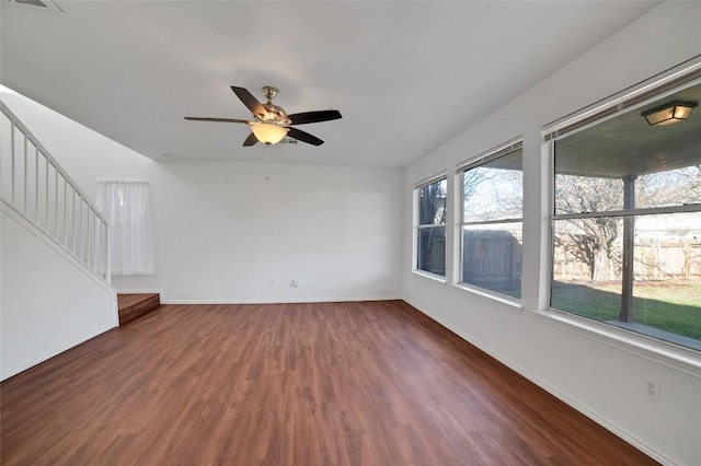 unfurnished living room with stairway, baseboards, wood finished floors, and a ceiling fan