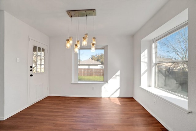 unfurnished dining area featuring wood finished floors and baseboards