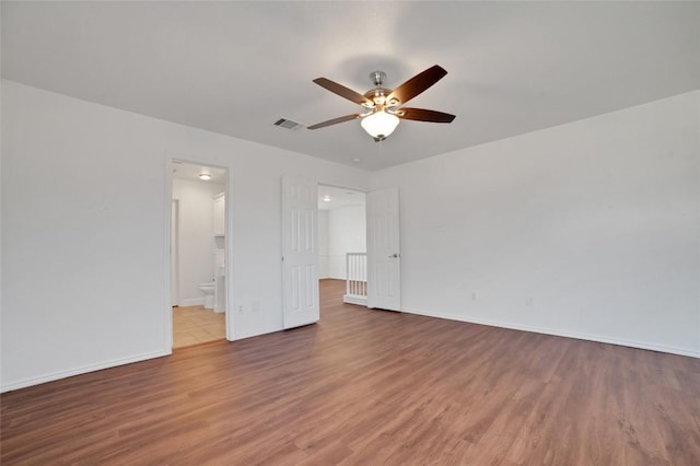 interior space featuring visible vents, baseboards, a ceiling fan, and wood finished floors