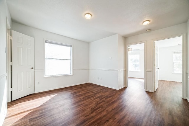 spare room with baseboards and dark wood-style flooring