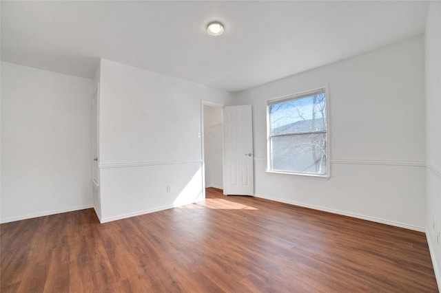 spare room featuring baseboards and wood finished floors