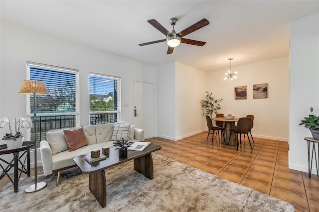 living area with tile patterned floors, ceiling fan with notable chandelier, and baseboards