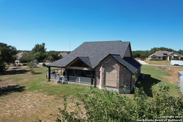320 Mill Run, New Braunfels, TX 78132 - view of side of home featuring brick siding, a shingled roof, covered porch, and a lawn