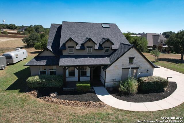 320 Mill Run, New Braunfels, TX 78132 - view of front of home with a front lawn, a shingled roof, covered porch, and stone siding
