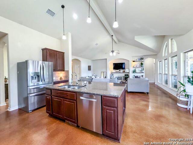320 Mill Run, New Braunfels, TX 78132 - kitchen with stainless steel appliances, arched walkways, a sink, beamed ceiling, and an island with sink