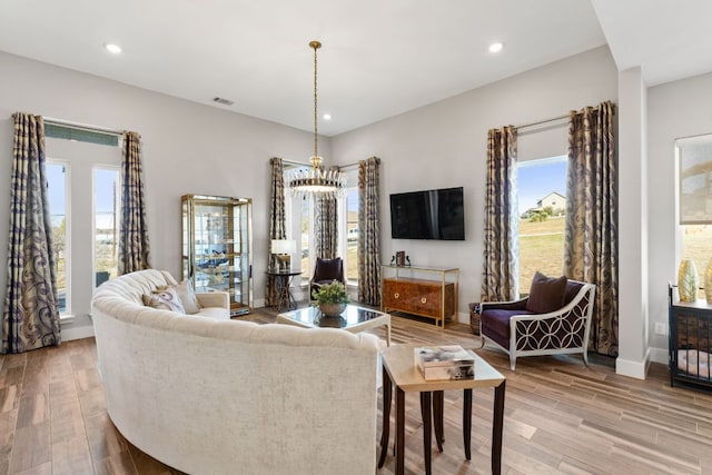 living area featuring light wood finished floors, recessed lighting, and an inviting chandelier