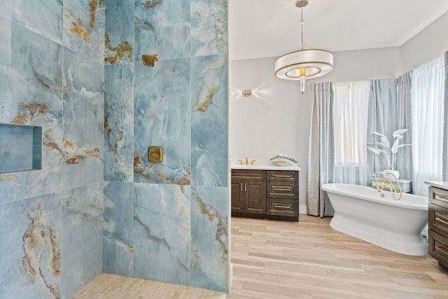 full bath featuring vanity, a soaking tub, and wood finished floors