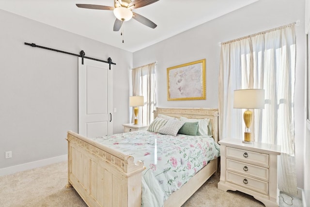 bedroom with a ceiling fan, a barn door, light colored carpet, and baseboards