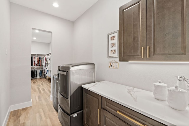 laundry area featuring baseboards, washing machine and clothes dryer, recessed lighting, cabinet space, and light wood-type flooring