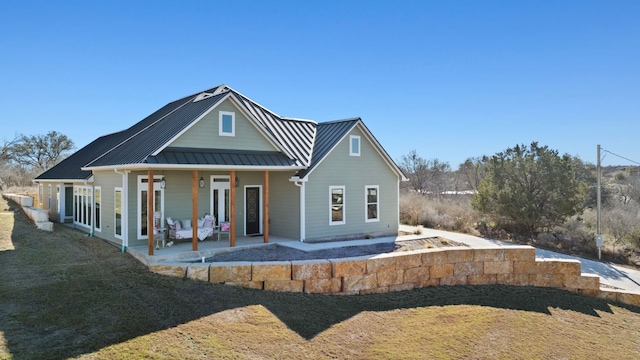 back of property featuring a standing seam roof, a patio, a lawn, and metal roof