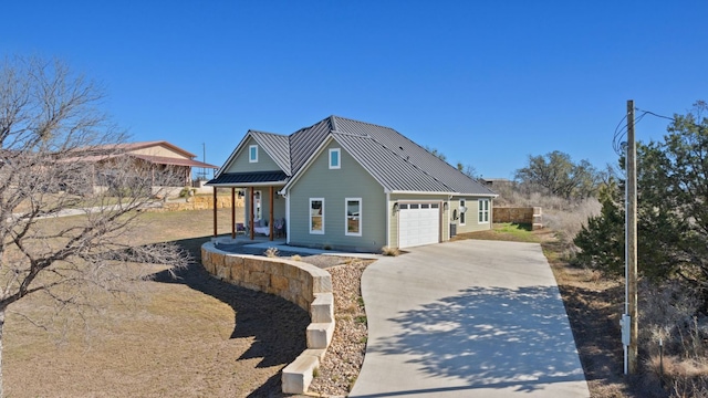 view of front of home with a standing seam roof, a porch, an attached garage, concrete driveway, and metal roof