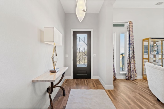 entryway with wood finished floors, visible vents, and baseboards