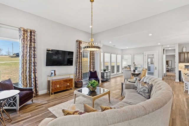 living area with recessed lighting, a notable chandelier, and light wood finished floors