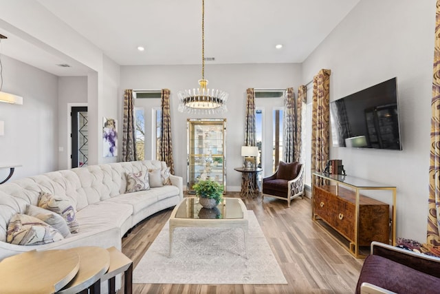 living room with recessed lighting, plenty of natural light, a notable chandelier, and wood finished floors