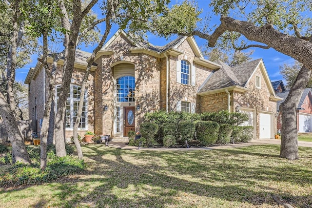 traditional-style home with an attached garage, a shingled roof, a front lawn, stone siding, and driveway