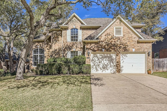 traditional-style house featuring a front lawn, fence, roof with shingles, a garage, and driveway