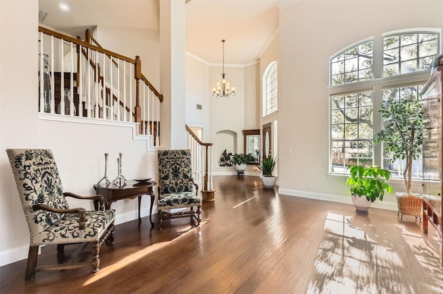 living area with crown molding, baseboards, stairway, wood finished floors, and a notable chandelier