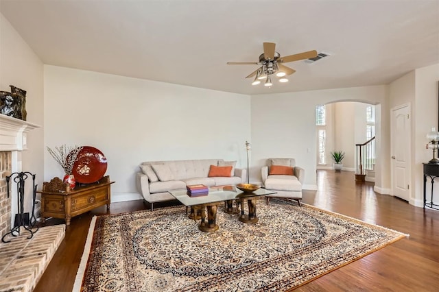 living room with wood finished floors, visible vents, arched walkways, and ceiling fan