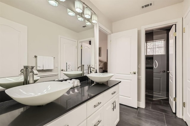 full bath with a sink, visible vents, and double vanity