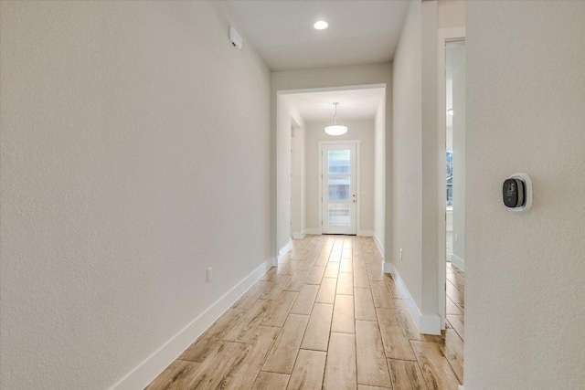 hallway featuring light wood-style flooring and baseboards