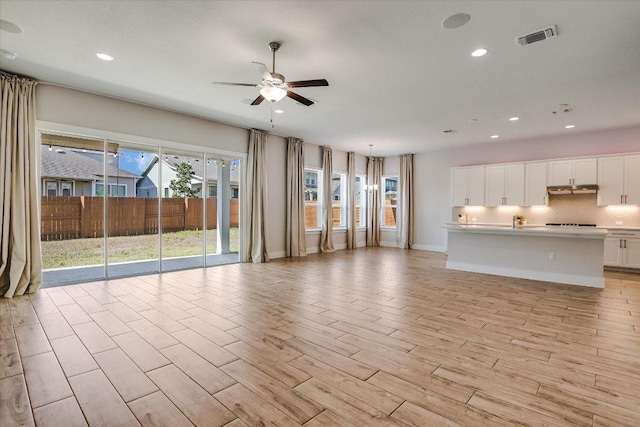 unfurnished living room featuring light wood-type flooring, visible vents, a ceiling fan, recessed lighting, and baseboards