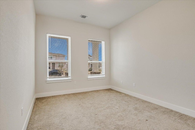 carpeted spare room with visible vents and baseboards