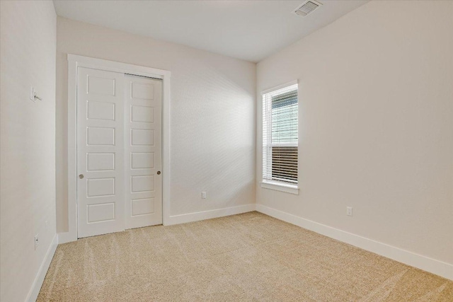 unfurnished bedroom with baseboards, visible vents, a closet, and light carpet