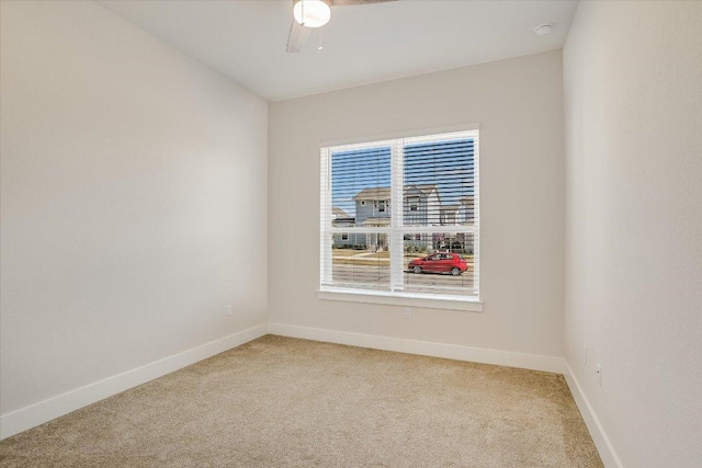 spare room with ceiling fan, baseboards, and light carpet