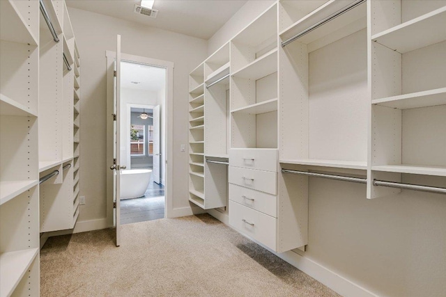 walk in closet with visible vents and light colored carpet