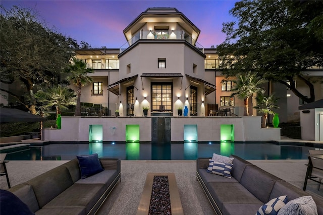 back of house featuring stucco siding, a patio, outdoor lounge area, and a balcony