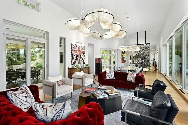 living area featuring wood finished floors, a towering ceiling, and a chandelier