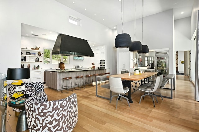 dining area featuring recessed lighting, light wood-type flooring, and a high ceiling