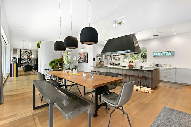 dining space with recessed lighting, light wood-type flooring, plenty of natural light, and a high ceiling