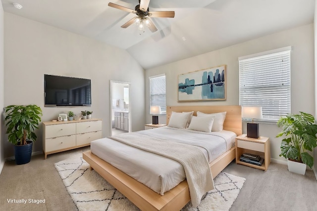 bedroom featuring baseboards, vaulted ceiling, light carpet, ensuite bathroom, and a ceiling fan