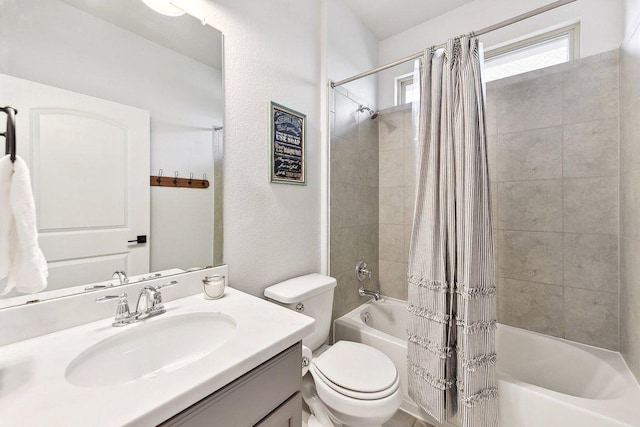 bathroom with toilet, shower / bath combo with shower curtain, vanity, and a textured wall